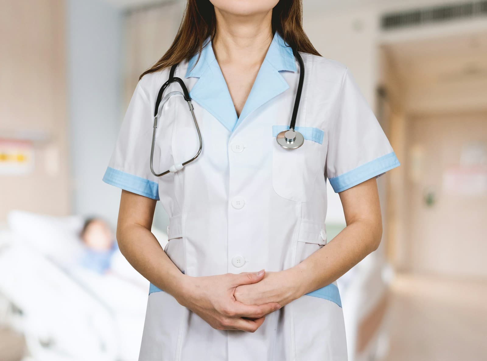 A clinician in whites with a stethoscope on a hospital ward